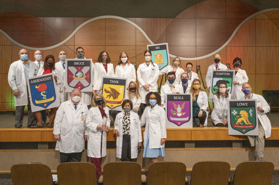 Faculty posing with house crests at the 2021 White Coat Ceremony
