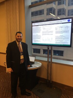 Pediatric Anesthesia Fellow standing in front of a screen with his poster presentation