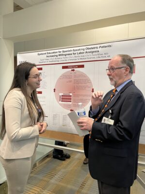 Faculty member talks to a resident about her research poster