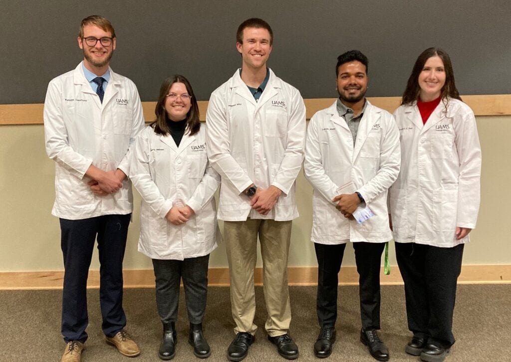 Photo of students who passed their candidacy exams wearing their white coats.