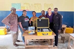 Group of people posing with portable hearing measurement device in a Sierra Leone classroom