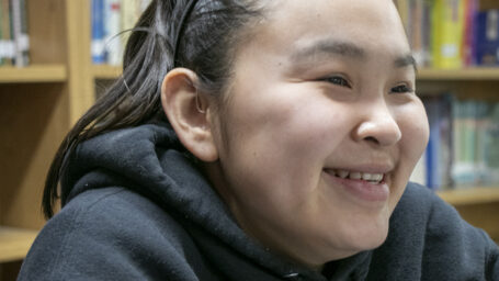 Girl smiling in clinic. She is wearing a hearing assistance device.