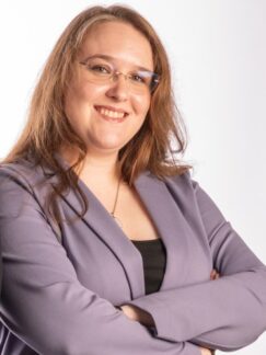 Amanda Blagg Head-and-shoulders portrait of a woman in her mid-thirties with long reddish brown hair, looking at the camera in soft lighting.