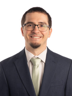 Benji Nicholas, MDiv Young professional gentleman with dark hair and glasses in dark suit