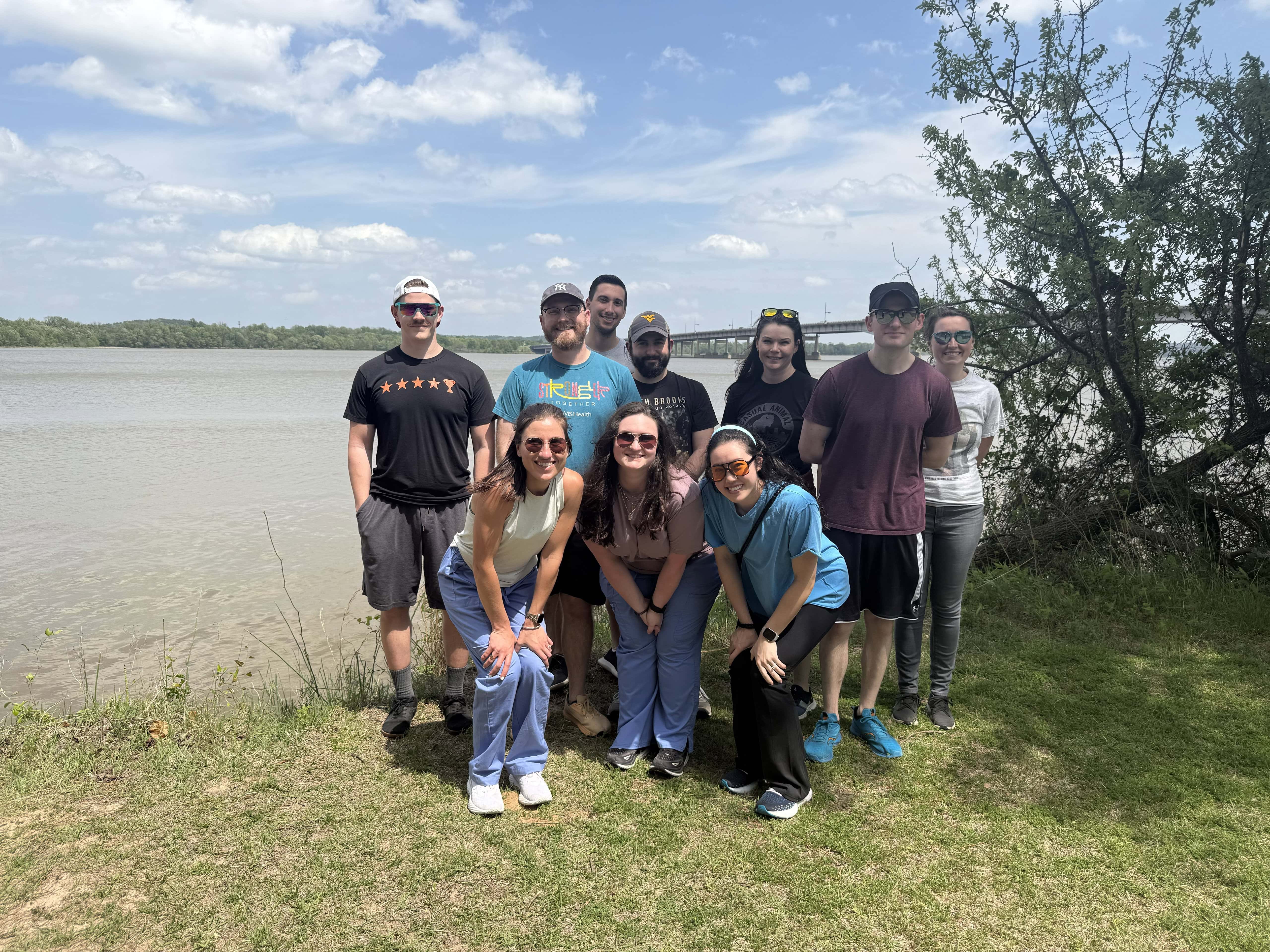 Group photo of PGY-2 residents. The group is outdoors in casual clothing. The Arkansas river is in the background.