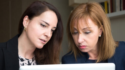 Portrait of two mature business women looking a laptop.