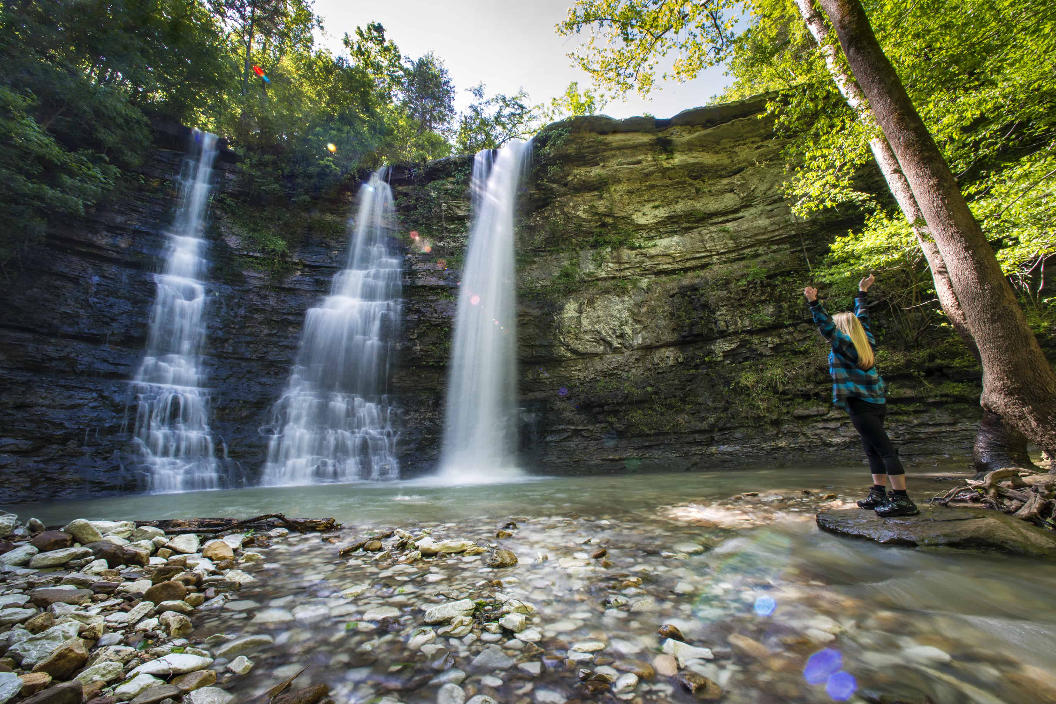 Woman standing next to triple falls at Kyles Landing