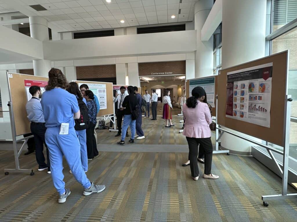 Students, Faculty and Staff reviewing and discussing posters. 