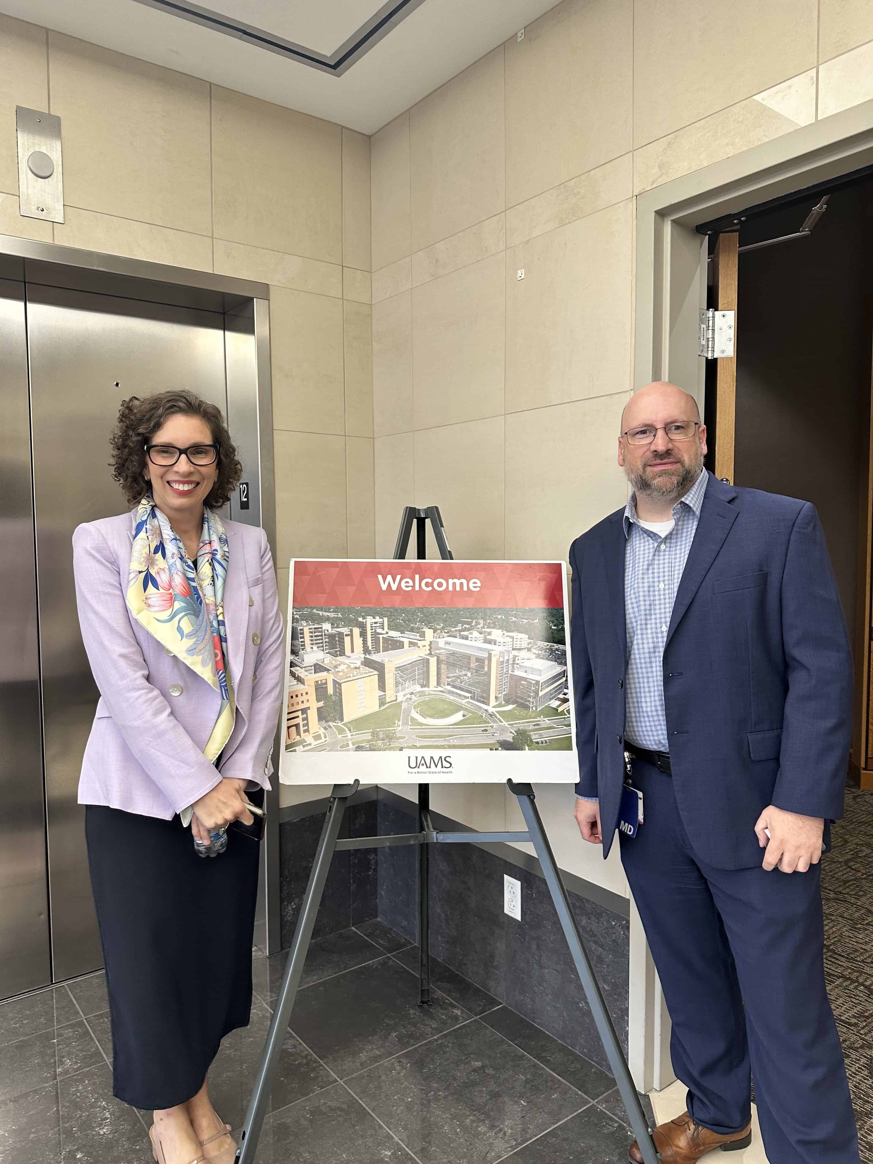 Faculty members posing by a UAMS poster