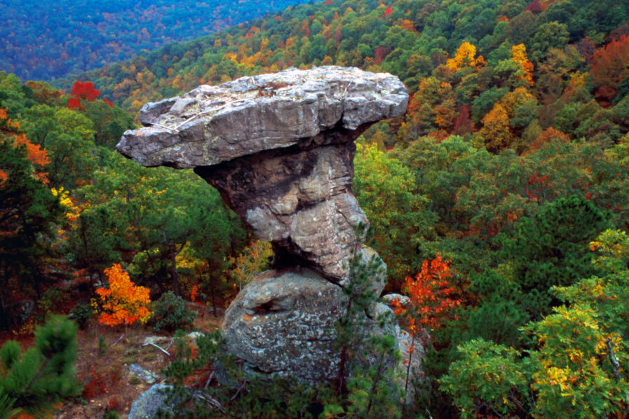 large pedestal rock with autumn-colored trees in a valley in the background