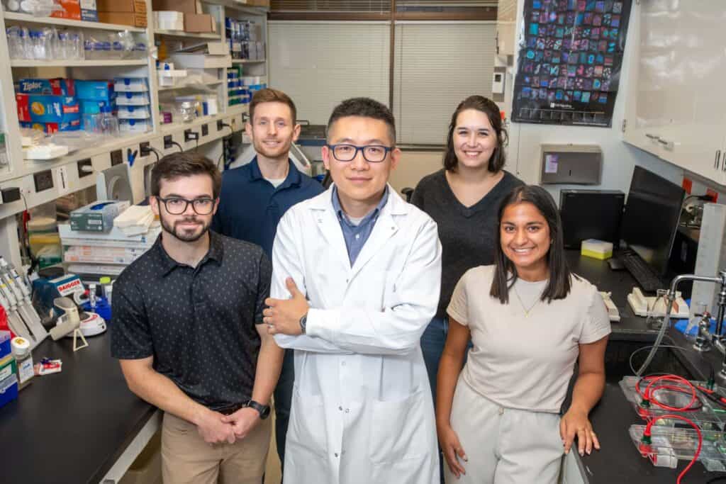 Dr. Huang poses with his lab members in a lab on the UAMS campus