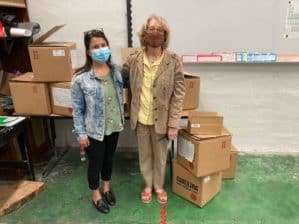 Two women posing beside boxes of scientific equipment
