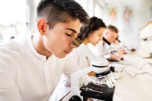 high school students with microscopes in laboratory