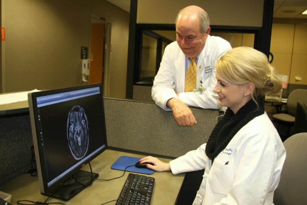 Doctor looks at a computer screen while another looks on