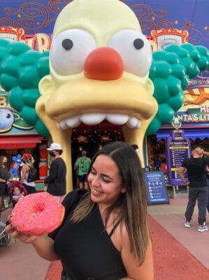 Sama Almasri posing with a giant donut in front of a Crusty the Clown building