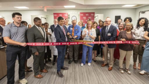 Rohit Dhall, M.D., prepares to cut the ribbon officially opening the UAMS Health Neurology Clinic in the Doctors Building as Jonathan Goree, M.D., (left of Dhall, front row), and Scott Lucchese (right of Dhall, front row), Michelle Krause, M.D., and Ron Robertson, M.D., look on. Image by Evan Lewis