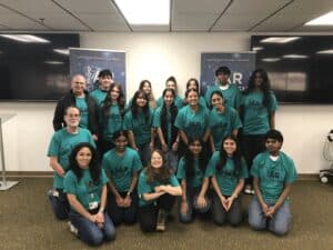 Group of STEM ambassadors pose with faculty members. They are all wearing teal colored AR Tech Dash shirts