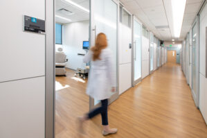 blurred image of an APRN coming out of an exam room into the hallway