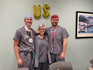 group of seniors in scrubs and surgical hats, standing together and smiling for the camera