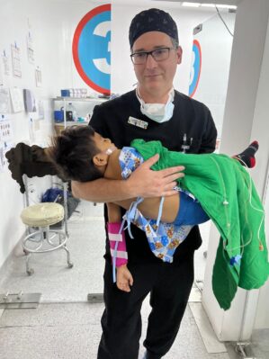 Dr. Larry Hartzell holding a small patient in a procedure room