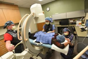 Wide shot of procedure room with doctor and nurses attending to a patient