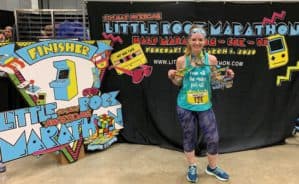 Woman in running gear posing with medals at the end of the Little Rock Marathon.