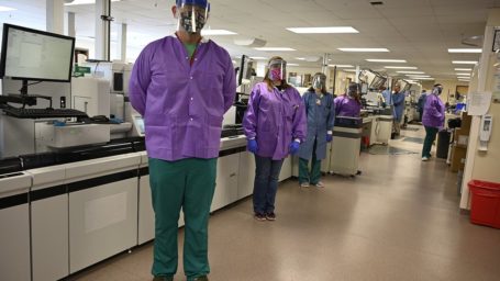 Lab workers standing in front of equipment in the UAMS Clinical Lab