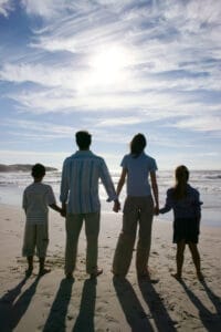 A family stands on a beach holding hands