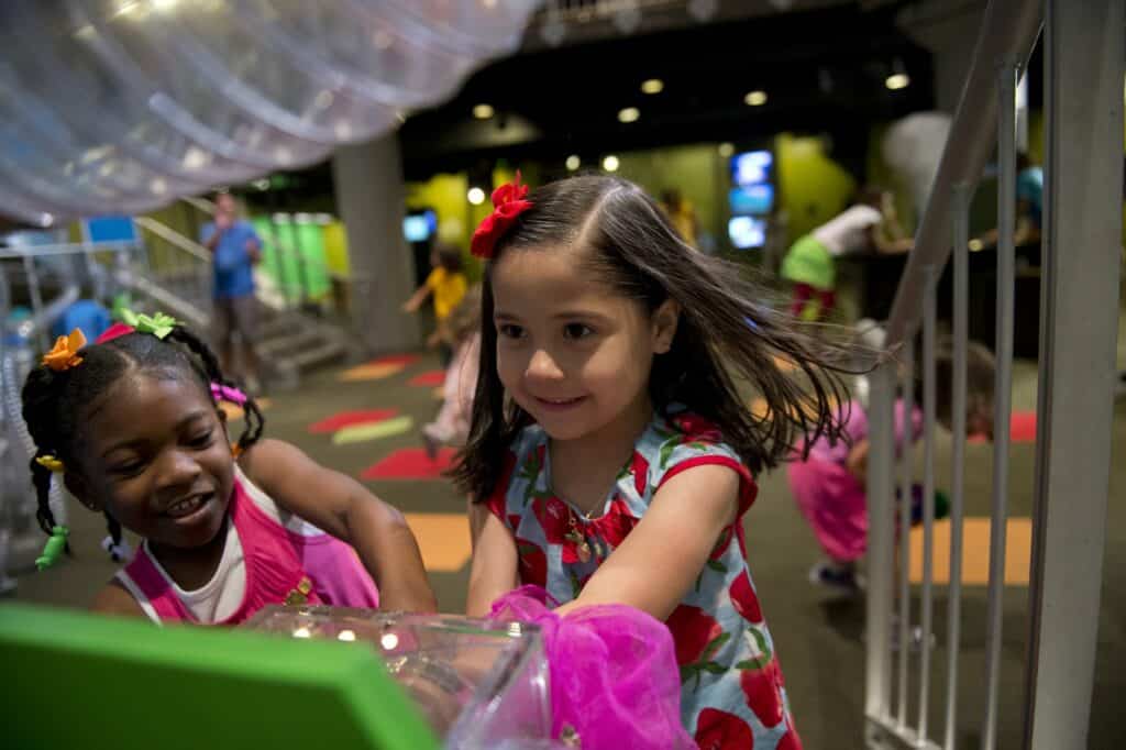 Two young girls play with a hands-on exhibit at the Museum of Discovery in Little Rock