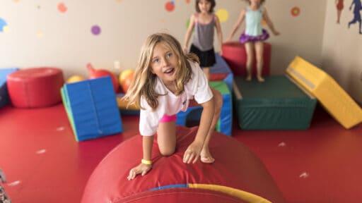 children jump on red play equipment in colorful room