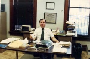 Dr. Robert Arrington sits at his desk, circa 1975