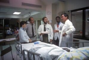 Robert H. Fiser instructs a group of physicians near a patient bed