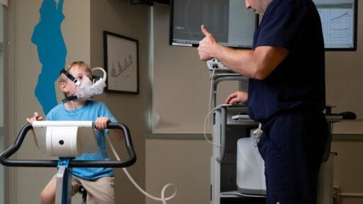 boy on exercise bike with oxygen max looks at a nurse giving thumbs up