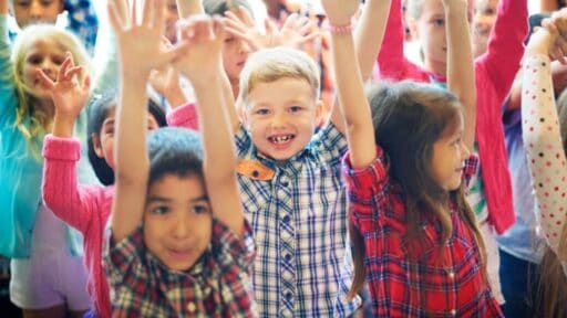A group of happy children standing with their arms in the air