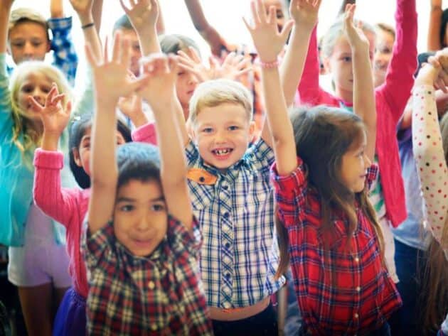 A group of happy children standing with their arms in the air