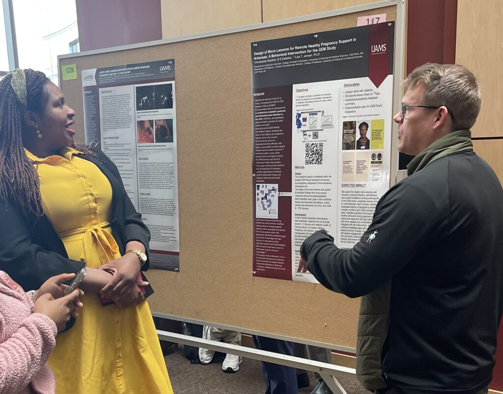 Christopher Mayfield (right) discusses his scientific poster with a guest of UAMS Student Research Day (left).
