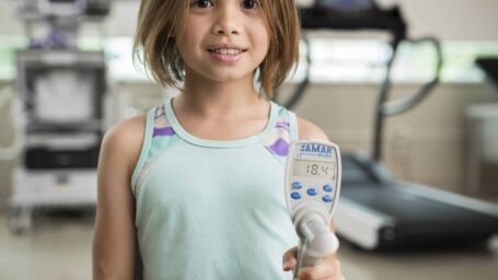 a girl uses a hand-held strength-testing instrument