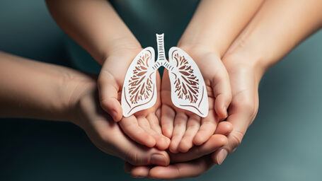Child s and adult s hands holding paper lungs.