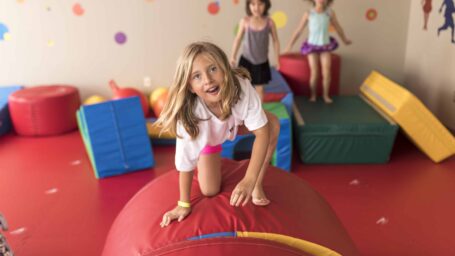 children jump on red play equipment in colorful room