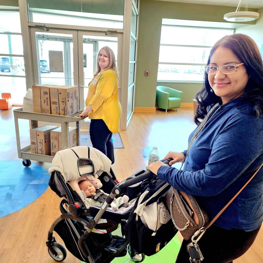 woman with stroller in front of a cart of boxed clean diapers