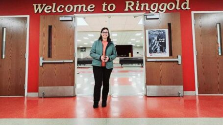 researcher standing in a school lobby under the wording Welcome to Ringgold