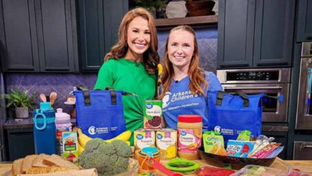 dietitian and news anchor stand before a counter with kids lunch options