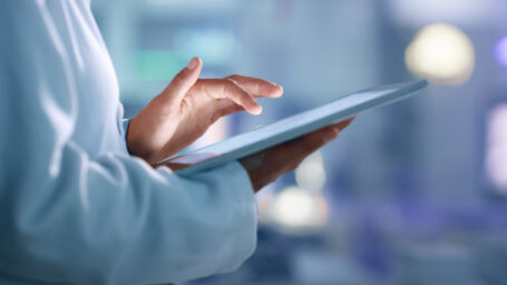 Close up of researcher's left hand hovering over a tablet