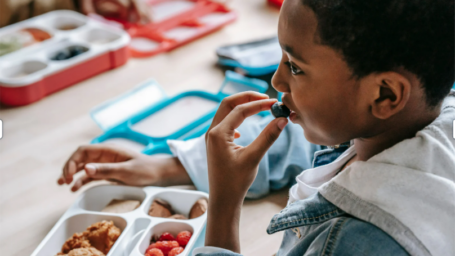 boy eating blueberry out of school lunch