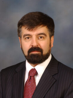Alexei G. Basnakian, M.D., Ph.D., D.Sc. Headshot of Dr. Basnakian in a suit with red tie on a blue watercolor background