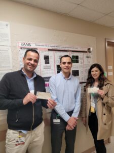 Dr. Fouda with two lab members. The lab members are holding award checks.