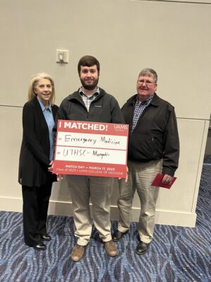 Garrett Graham posing with his parents. He is holding a board that says I Matched! Emergency Medicine at UTHSC-Memphis