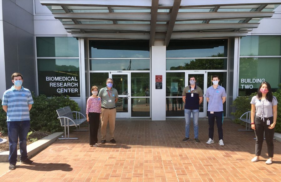 Lab group wearing masks outside Biomedical Two building
