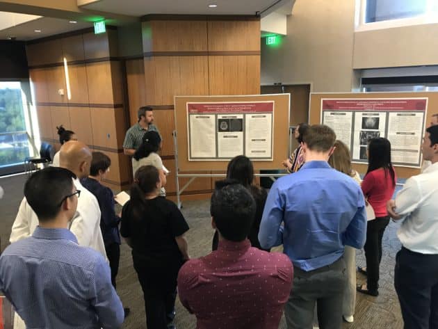 group of residents observing a presentation in front of a research poster