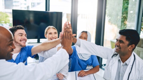 Cropped shot of a group of medical workers high fiving during a meeting in their hospital boardroom
